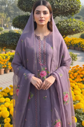 Woman in a purple embroidered outfit standing in a garden with flowers and greenery.